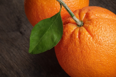 ripe round orange with stem and leaf on wooden table, selective focusの写真素材