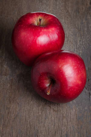 two ripe red apples close up, on old wood tableの写真素材