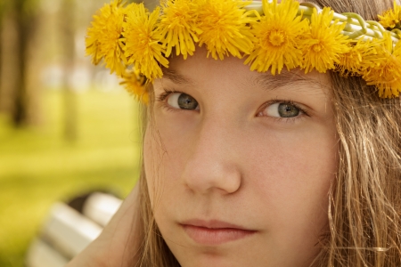 portrait of young teenager girl on bench with wreath of dandelions, summer timeの写真素材