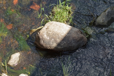 rocks in river, big rock in center half shadowの写真素材