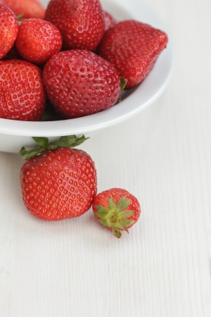 ripe strawberries in bowl, on white wooden tableの写真素材