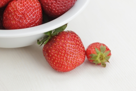 ripe strawberries in bowl, on white wooden tableの写真素材