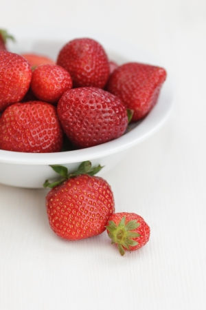 ripe strawberries in bowl, on white wooden tableの写真素材
