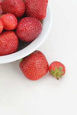 ripe strawberries in bowl, on white wooden tableの写真素材