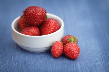 ripe strawberries in bowl, on blue wooden tableの写真素材