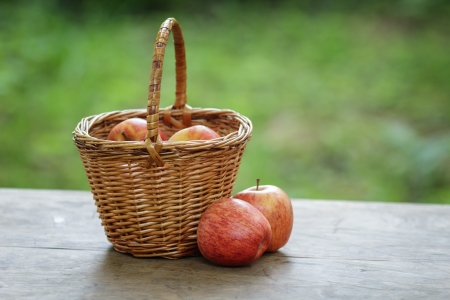 gala apples in a wicker basket, on wooden tableの写真素材