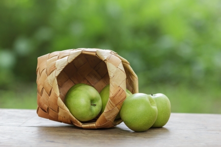 green apples in a birchbark basket, on wooden tableの写真素材