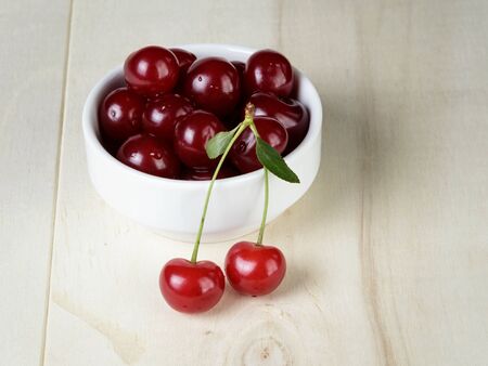 ripe cherries in bowl, on wooden tableの写真素材