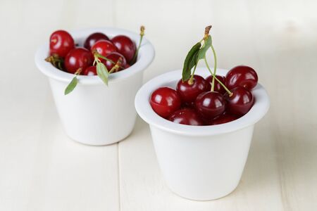 ripe cherries in bowl, on wooden tableの写真素材