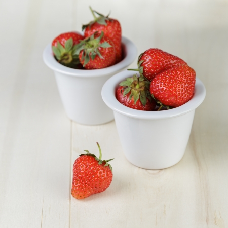 ripe strawberries in bowl, on wood tableの写真素材