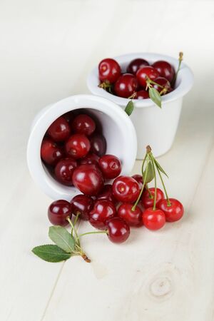 ripe cherries in bowl, on wooden tableの写真素材