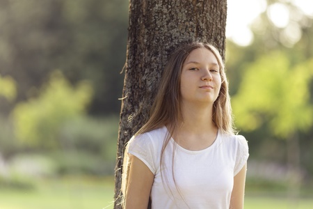 young girl leaning on a tree, horizontalの写真素材