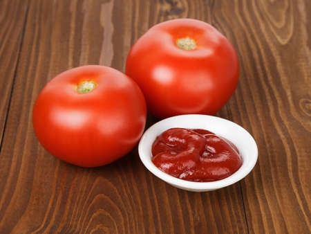 tomato sauce in bowl on wooden table, with tomato