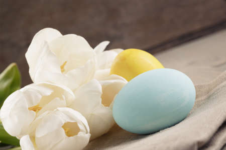 pastel color easter eggs with tulips on table, slightly toned photo