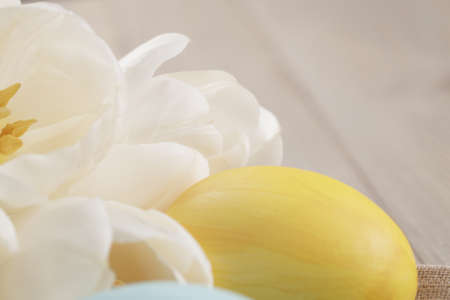 pastel color easter eggs with tulips on table, slightly toned photo