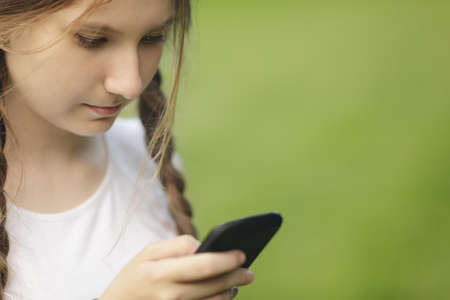 teen girl using mobile phone outdoors in parkの写真素材