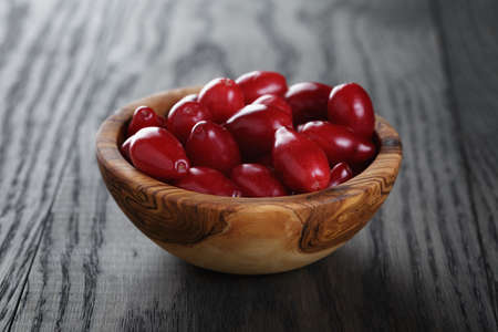 ripe cornel berrys in bowl, on old wood tableの写真素材