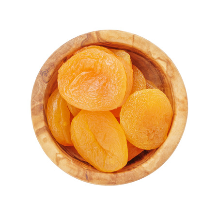 heap of dried apricots in wood bowl from above, isolated on white backgroundの写真素材
