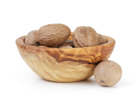 whole dried nutmegs in bowl, isolated on whiteの写真素材