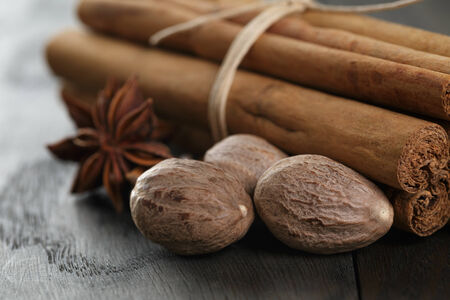 bunch of cinnamon sticks with nutmeg and anise star, on rustic oak tableの写真素材