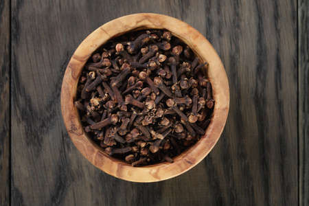 cloves in olive bowl on oak table, christmas spiceの写真素材