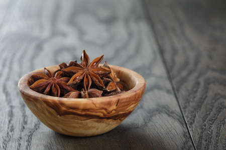 anise stars in olive bowl on oak table, rustic styleの写真素材
