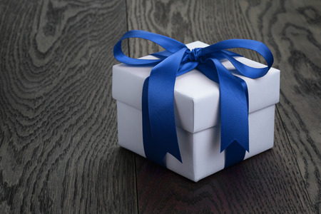 gift box with ribbon bow on old oak table, copy space on the left