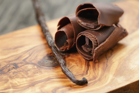 three peeled chocolate curls on olive wood board, closeup photoの写真素材