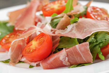 salad with prosciutto arugula and tomatoes on wooden tableの写真素材