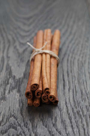 bunch of cinnamon sticks tied with twine, on rustic oak tableの写真素材
