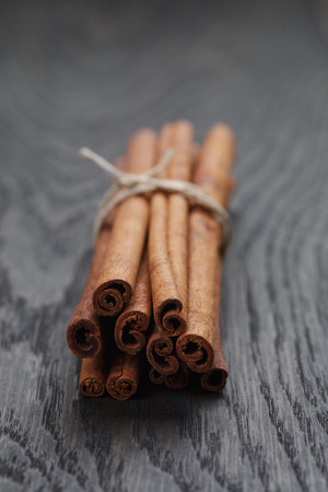 bunch of cinnamon sticks tied with twine, on rustic oak tableの写真素材