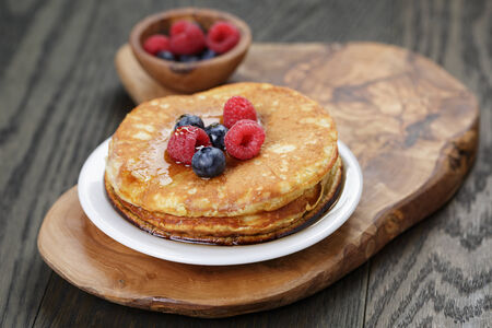 Pancakes with raspberry, blueberry and maple syrup, on oak wooden tableの写真素材