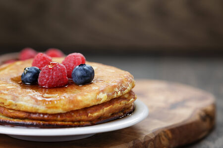Pancakes with raspberry, blueberry and maple syrup, on oak wooden tableの写真素材