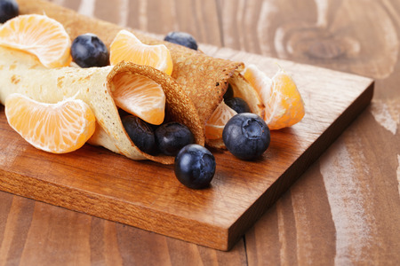 homemade blinis or crepes with blueberries and jam, on wooden tableの写真素材