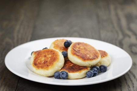 homemade curd fritters on plate with berries, wooden tableの写真素材
