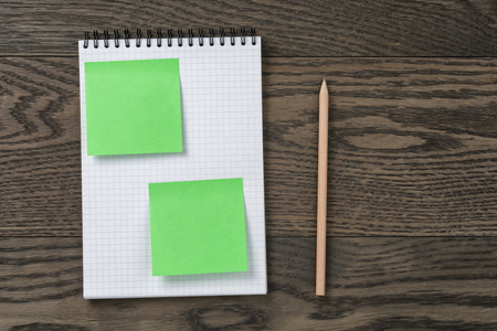 notebook with pencil and sticky notes on oak wood table, top viewの写真素材