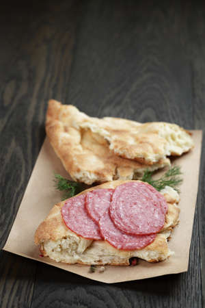 sandwich with pita bread and salami on wood table, rustic style