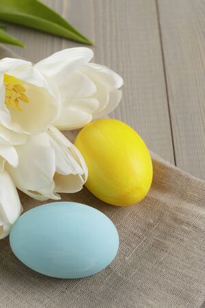 easter eggs and white tulips on wood table, paper card for textの写真素材