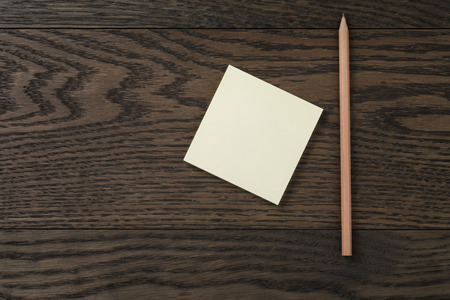 sticky note reminder on oak wood table with pencil