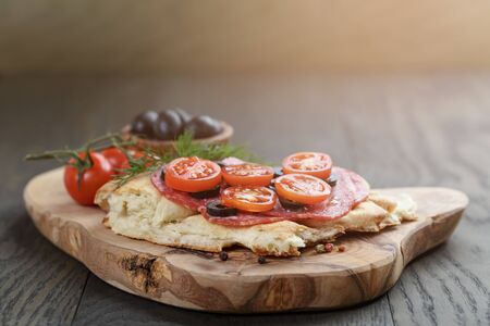 flat pita bread with salami and vegetables on wood tableの写真素材