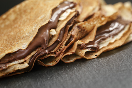 thin crepes or blinis with chocolate cream on slate boardの写真素材