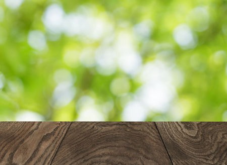 empty wooden table with green summer bokeh backgroundの写真素材