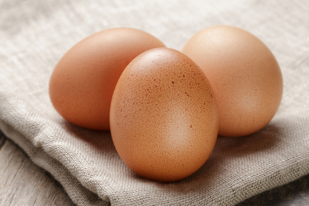 whole raw brown eggs closeup on wood table, rustic photoの写真素材
