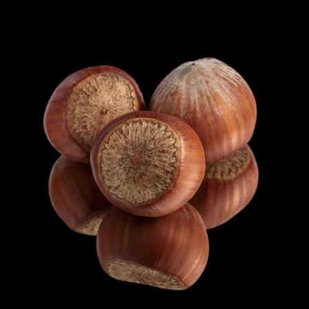 three hazelnuts on mirror, isolated on blackの写真素材