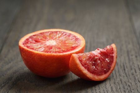 half and section of red orange on wooden tableの写真素材