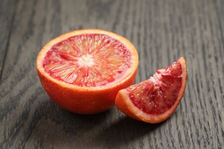 half and section of red orange on wooden tableの写真素材