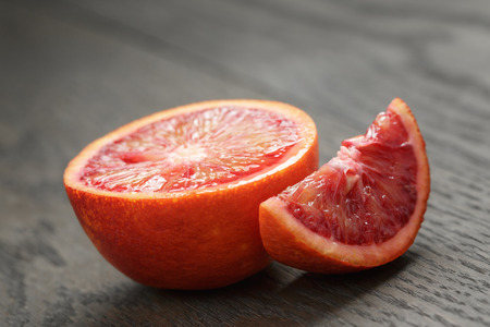 half and section of red orange on wooden tableの写真素材
