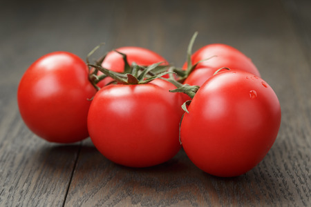 ripe wet tomatoes on vine on wood tableの写真素材