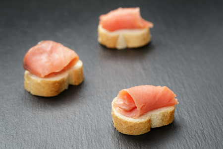 baguette slices with curred salmon on slate backgroundの写真素材