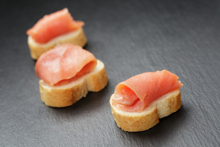 baguette slices with curred salmon on slate backgroundの写真素材